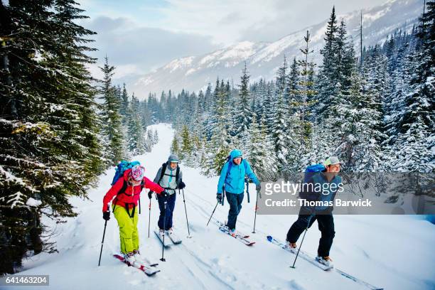 smiling friends ascending mountain during backcountry ski tour - skiing and snowboarding stockfoto's en -beelden