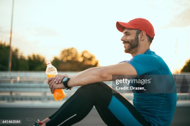 muscular athlete exercising outdoors, near the road in urban district in summer - sports drink stock pictures, royalty-free photos & images