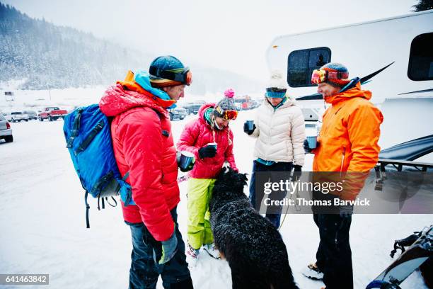 group of friends sharing champagne and playing with dog after returning from backcountry ski tour - motorhome winter stock-fotos und bilder