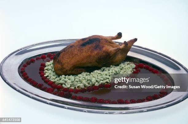 Close-up of canard aux framboises , on a serving plate and seen against a white background, at Lutece restaurant , New York, New York, 1984.