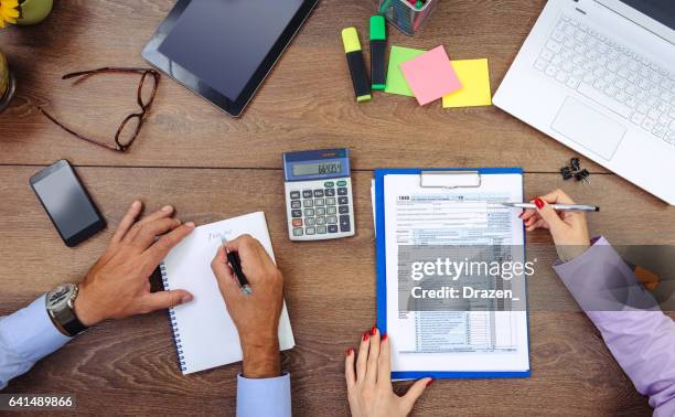 teamwerk in kantoor - man en vrouw die zich bezighouden met financiële gegevens, de belastingen en de aandelenmarkten - calculator tax forms stockfoto's en -beelden