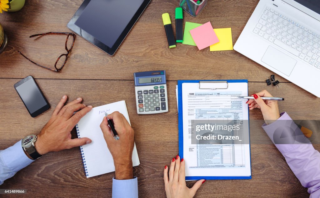 Teamwork in office - man and woman dealing with financial data, taxation and stock markets