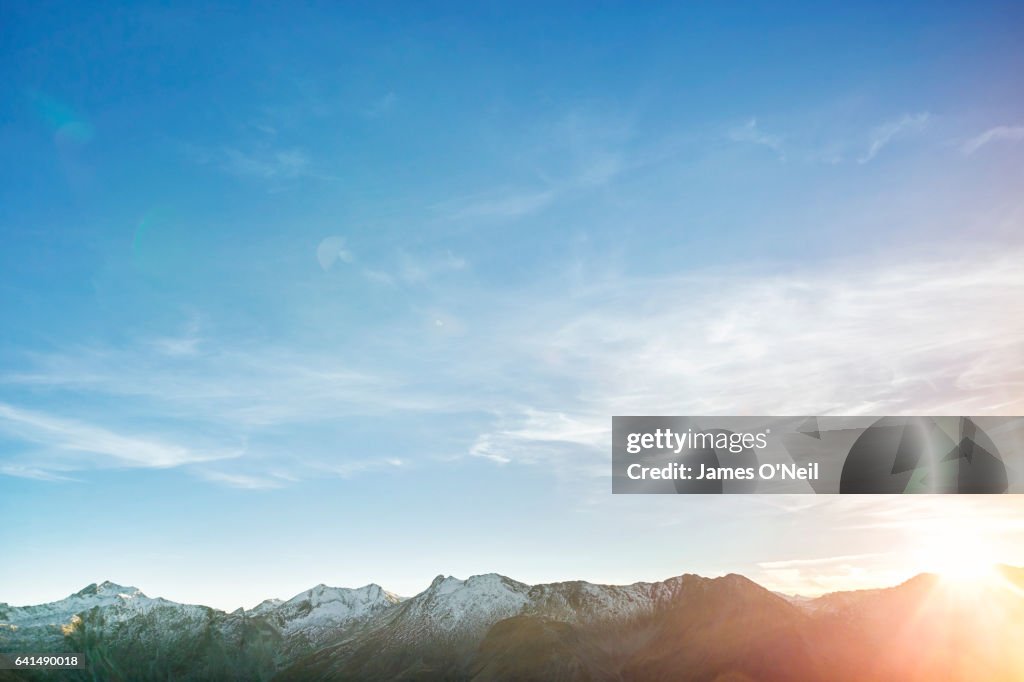 Low mountain range with expanse of sky and sun flare