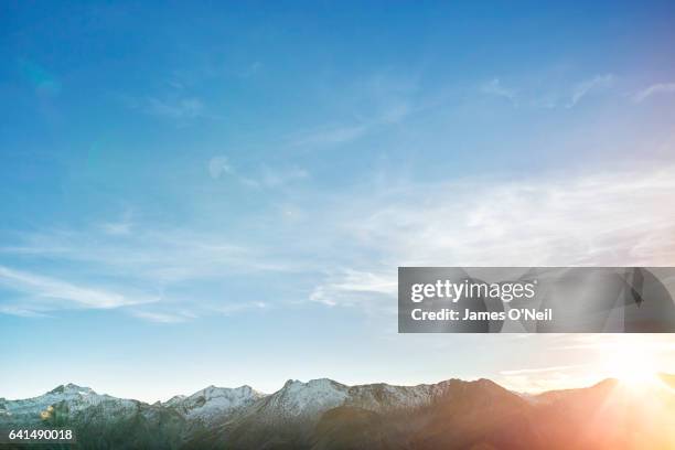 low mountain range with expanse of sky and sun flare - lucht stockfoto's en -beelden