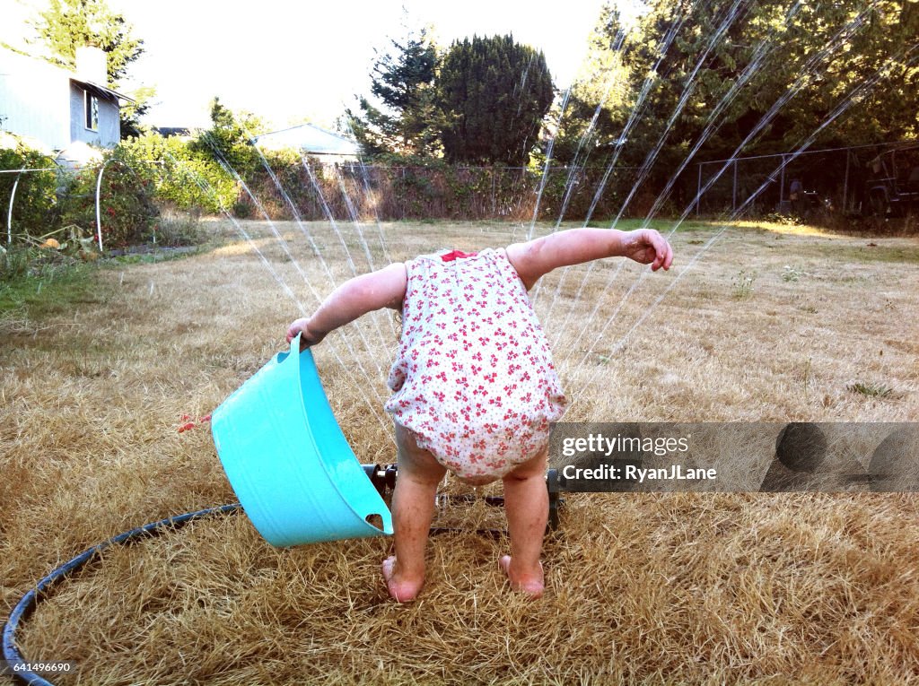 Menina brincando com chuveiro de incêndio (Sprinkler)