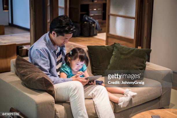 日本男と娘を一緒にタブレットを使用してソファの上に座って - japanese family ストックフォトと画像