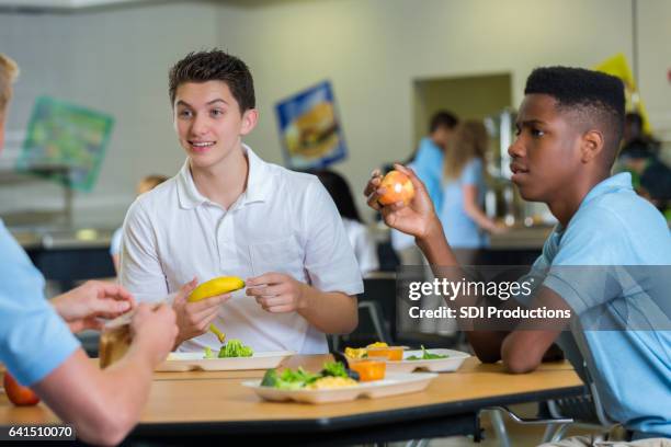 teenage boys eat lunch in school cafeteria - high school cafeteria stock pictures, royalty-free photos & images