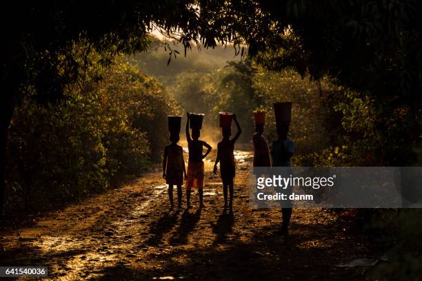 silhouette of woman carrying water and food on there head. madagascar, africa - madagascar stock pictures, royalty-free photos & images