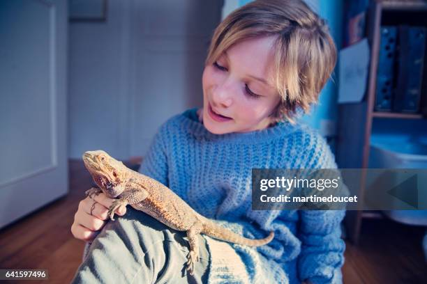 Young girl playing with her lizard pet in her bedroom.