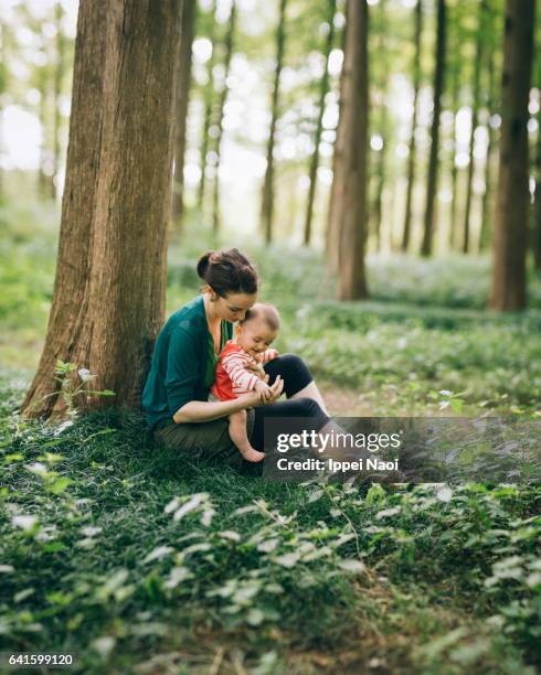 mother and baby sitting together in woods - mum sitting down with baby stockfoto's en -beelden