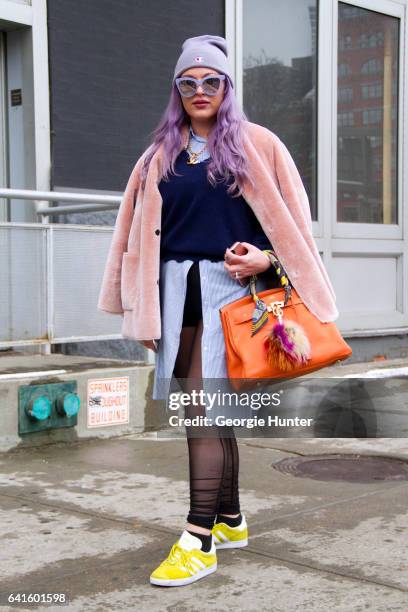 Guest is seen at Spring Studios outside the Lacoste show with purple dyed hair wearing light pink coat, purple sunglasses with mirror frames, blue...