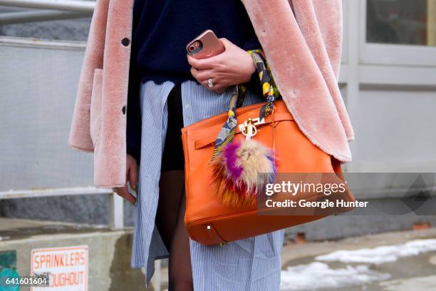 Guest is seen at Spring Studios outside the Lacoste show wearing light pink coat, blue over sized shirt, orange bag with faux fur pompoms and bandana...