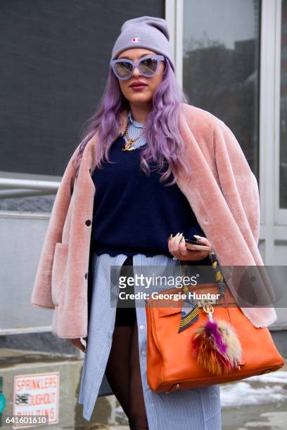 Guest is seen at Spring Studios outside the Lacoste show with purple dyed hair wearing light pink coat, purple sunglasses with mirror frames, blue...