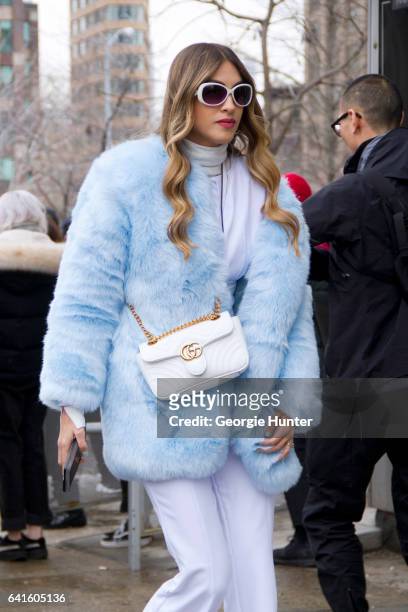 Guest is seen at Spring Studios outside the Lacoste show wearing pastel blue faux fur coat, white flared pants, white turtle neck, white rimmed...