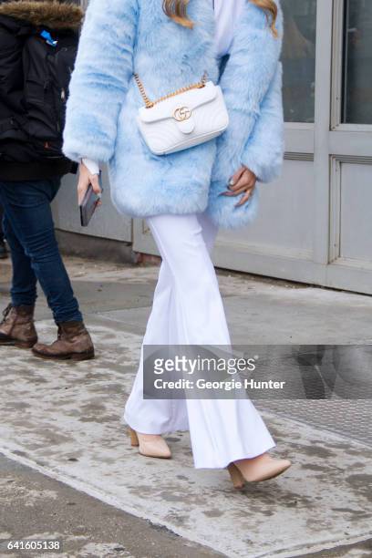 Guest is seen at Spring Studios outside the Lacoste show wearing pastel blue faux fur coat, white flared pants, white turtle neck, nude pointed toe...