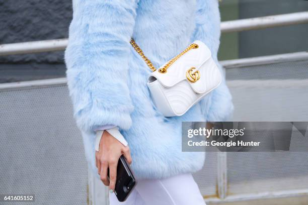 Guest is seen at Spring Studios outside the Lacoste show wearing pastel blue faux fur coat, white flared pants, white turtle neck and quilted white...
