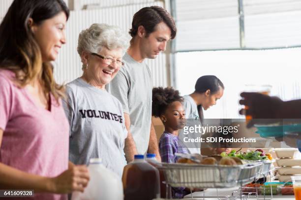 vrolijke diverse vrijwilligers samenwerken in gaarkeuken - vrijwilliger bedrijf stockfoto's en -beelden