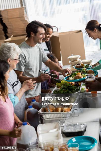 vriendelijke vrijwilligers dienen mensen in gaarkeuken - no kid hungry benefit dinner stockfoto's en -beelden