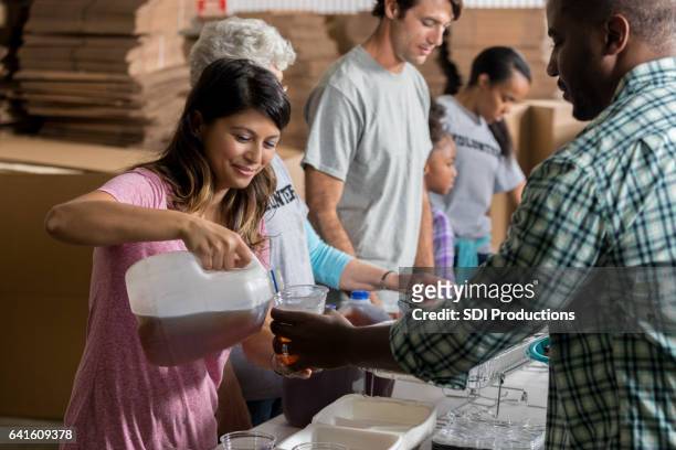 weibliche freiwillige gießt eistee für mann in der suppenküche - no kid hungry benefit dinner stock-fotos und bilder