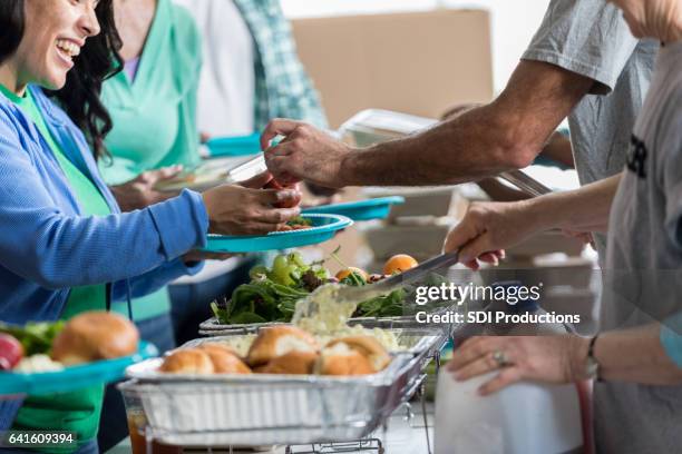 vrijwilligers dienen mensen in gaarkeuken - no kid hungry benefit dinner stockfoto's en -beelden