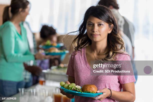 ernsthafte frau hält gesunde mahlzeit in der suppenküche - no kid hungry benefit dinner stock-fotos und bilder