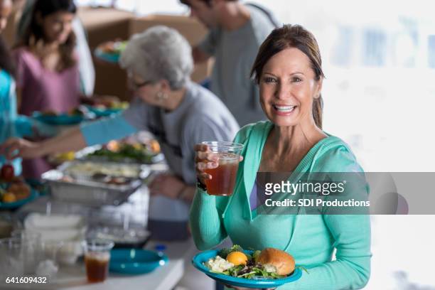 dankbaar volwassen kaukasische vrouw met voedsel in gaarkeuken - no kid hungry benefit dinner stockfoto's en -beelden