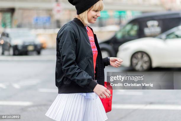 Guest wearing a red knit, Lacoste bag, beanie outside Lacoste on February 11, 2017 in New York City.
