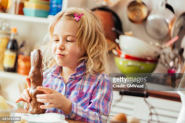 lindo niña pequeña apertura de chocolate conejo de pascua - easter bunny fotografías e imágenes de stock