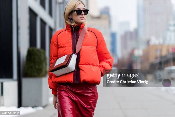 Camille Charriere wearing an orange down feather jacket, red pvc skirt, Converse sneaker outside Creatures of the Wind on February 11, 2017 in New...