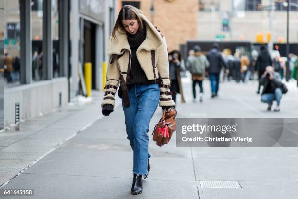 Irina Lakicevic wearing a turtleneck knit, beige sheepskin jacket, Loewe bag, denim outside Creatures of the Wind on February 11, 2017 in New York...