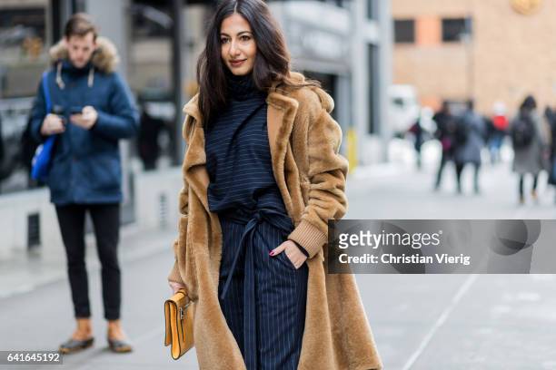 Nausheen Shah wearing a brown coat, clutch, striped pants, heels outside Creatures of the Wind on February 11, 2017 in New York City.