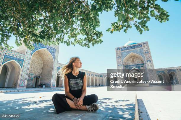 young woman relaxes in tranquil grounds of mosque - uzbekistan stock pictures, royalty-free photos & images