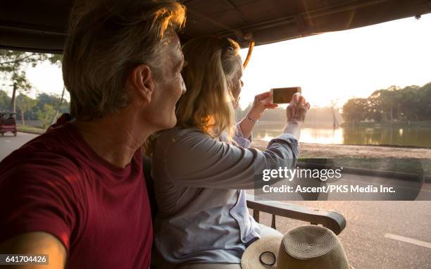 couple take smart phone pic from moving tuk tuk - tuk tuk stock pictures, royalty-free photos & images