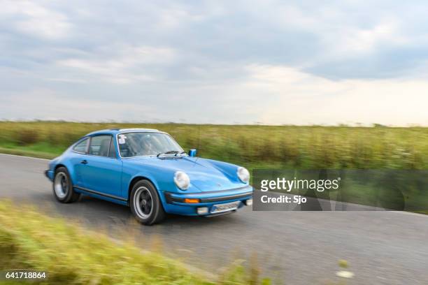 porsche 911 clásico coche deportivo de conducción en una carretera - porsche carrera fotografías e imágenes de stock
