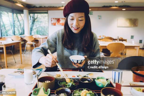 Joyful young woman is having meal in a Japanese restaurant