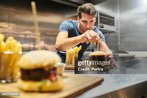 Chef preparing burger on plate at restaurant Chef preparing burger on plate at restaurant