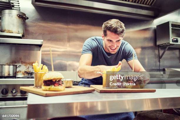 gelukkig chef-kok schikken hamburger en frietjes - burger and fries stockfoto's en -beelden