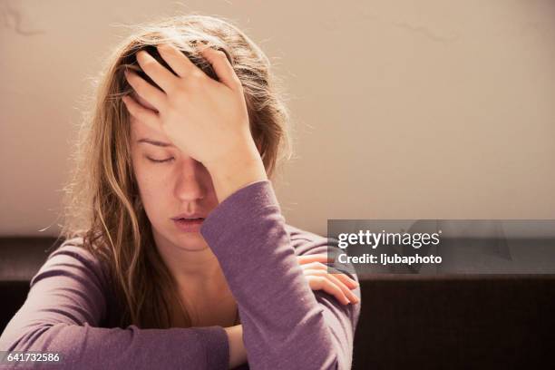 vrouw die lijden aan stress of een hoofdpijn grimassen in pijn - hoofdpijn vrouw stockfoto's en -beelden