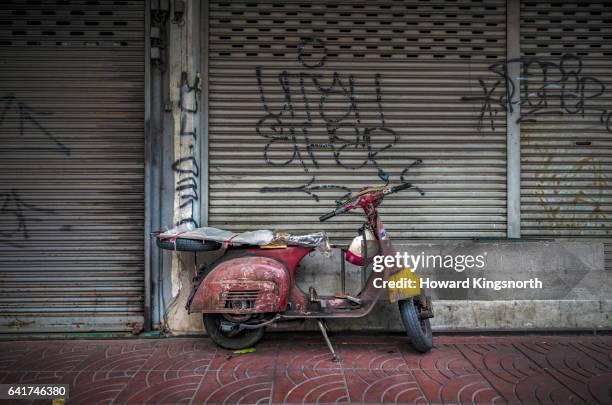 decrepit vintage motor scooter standing next to closed shopfront - industrial door stock pictures, royalty-free photos & images