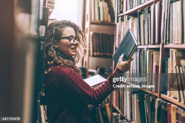 mujer en una biblioteca - libreria fotografías e imágenes de stock