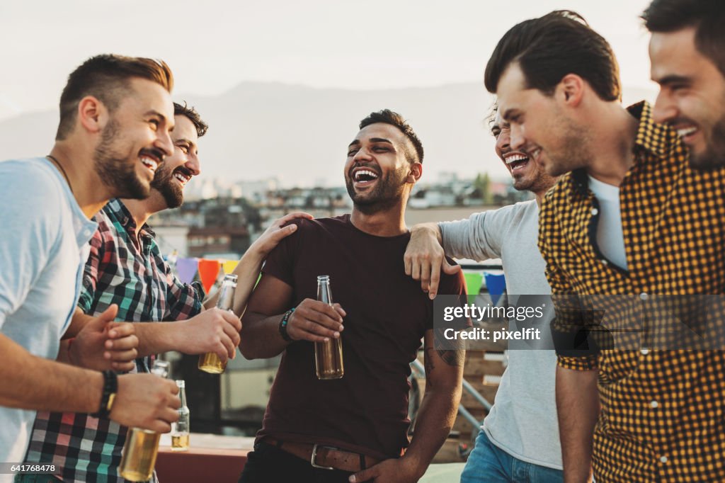 Multi-ethnic group of men laughing and drinking beer