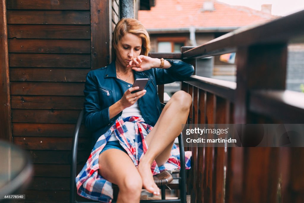 Young woman texting at the balcony