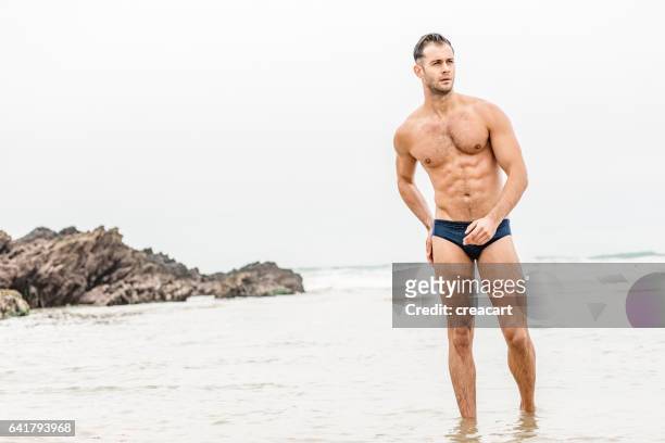 uomo muscoloso che esce dal mare, fistral beach, newquay - mens swimwear foto e immagini stock