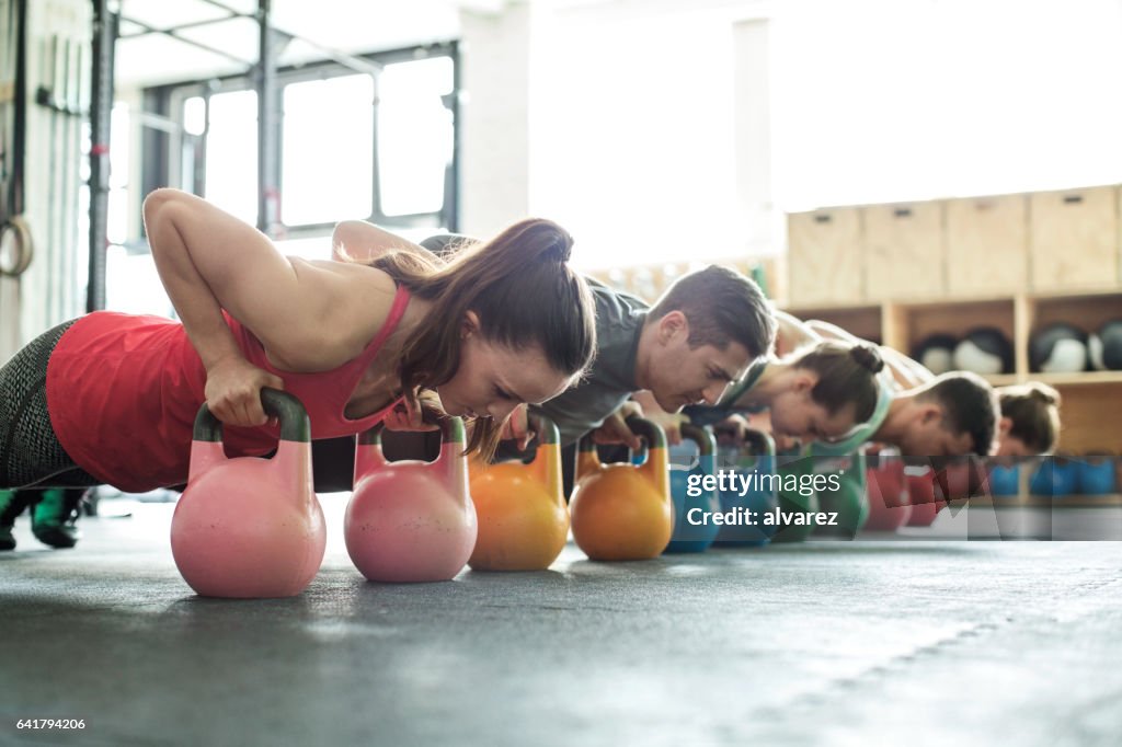 Fitness class doing push-ups with kettle-bells