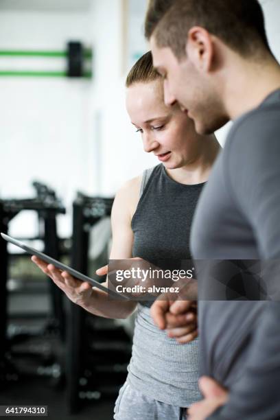 fitnesstrainer training plan bespreken met cliënt - sport tablet stockfoto's en -beelden