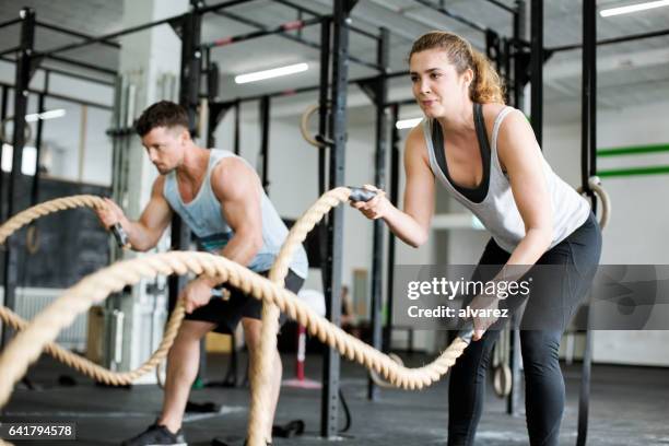fitness people working out with battle ropes - battle rope stock pictures, royalty-free photos & images