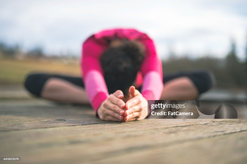 Young Hawaiian woman doing yoga outside by lake