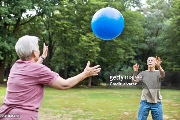 älteres paar training mit pilates ball im park - gymnastikball stock-fotos und bilder