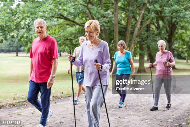 gruppe von senior zu fuß durch den park - walker stock-fotos und bilder