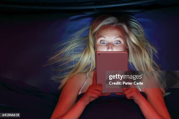 woman looking at tablet in bed, shocked expression - surprised woman looking at tablet stock pictures, royalty-free photos & images